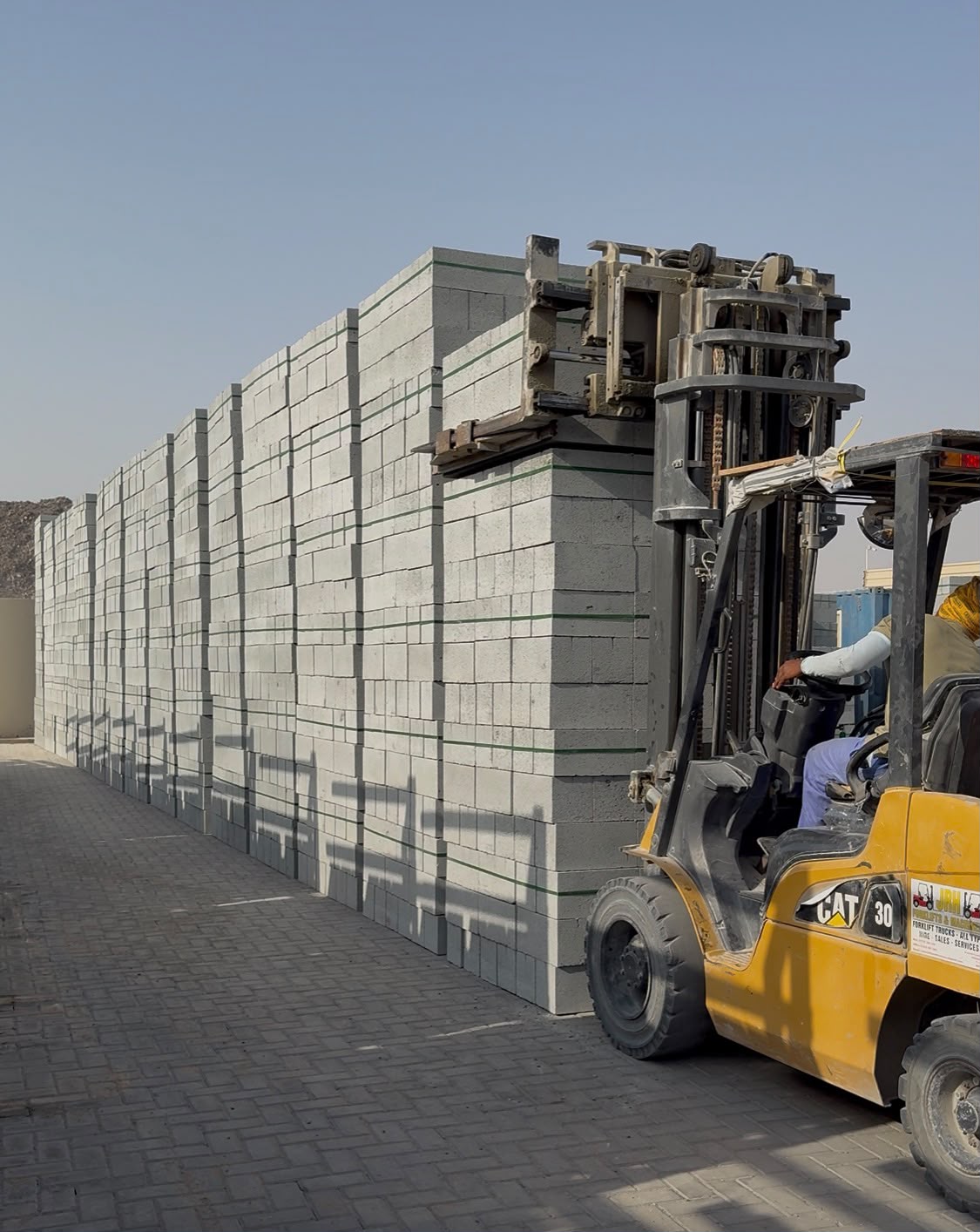 Forklift moving stacked concrete blocks in the yard